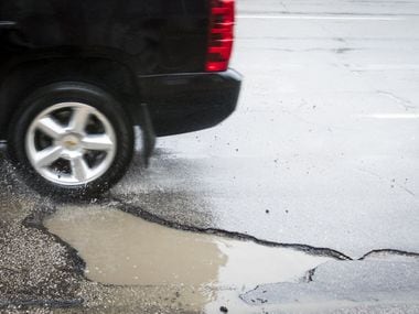 Water flies as a vehicle hits a pothole in the 3000 block of Harry Hines Blvd on Tuesday,...