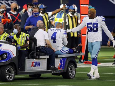 Dallas Cowboys defensive end Aldon Smith (58) comforts quarterback Dak Prescott (4) as he's carted off the field with an ankle injury against the New York Giants at AT&T Stadium Stadium in Arlington, Texas, Sunday, October 11, 2020.