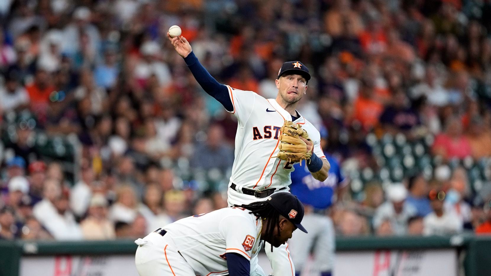 Houston Astros third baseman Alex Bregman, top, throws to first for the out after fielding a...