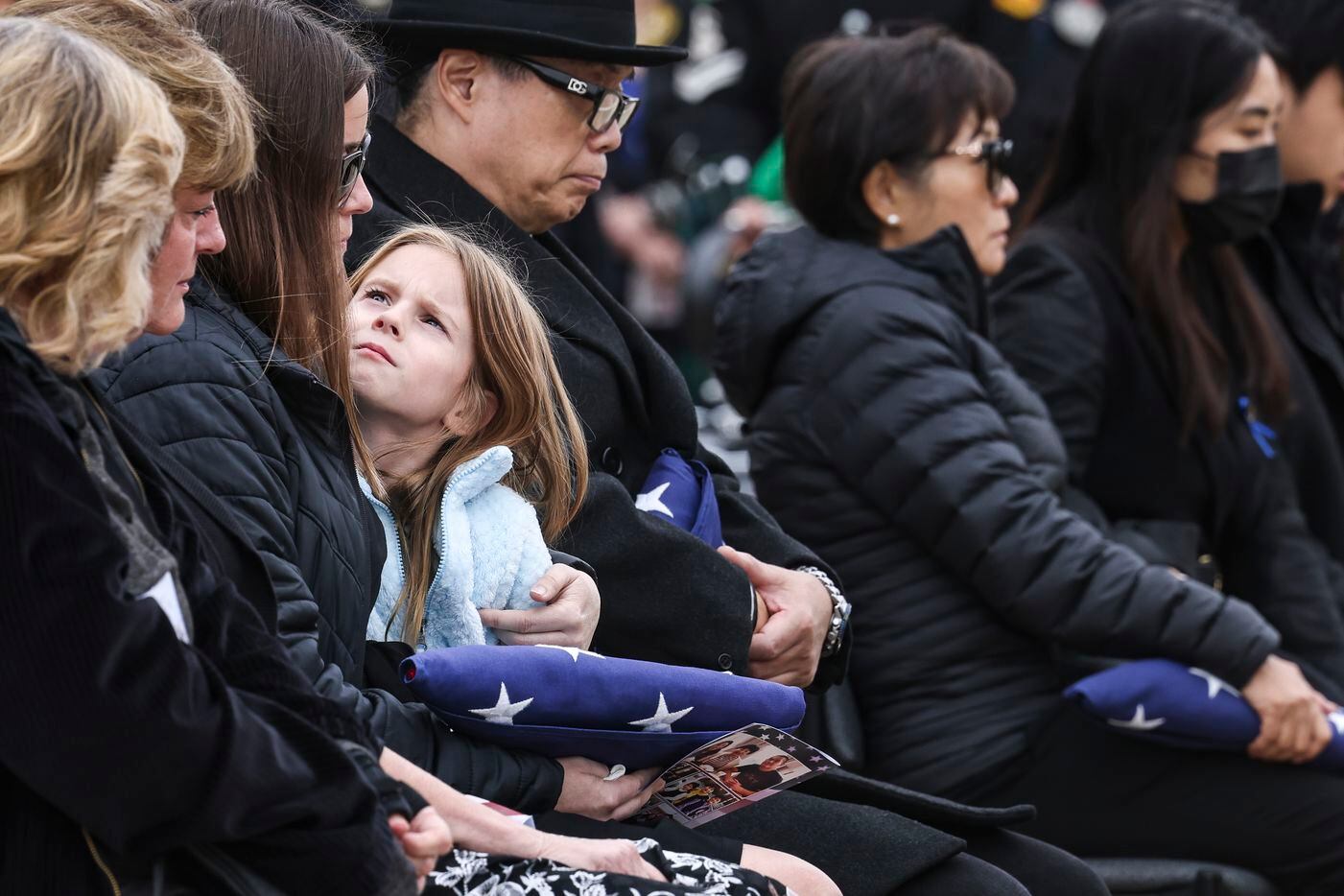 Kinsley Stout looks up at her mother Brittany after she is handed an American flag in memory...