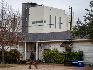 New construction rises over his home as Jose Morin walks between buildings on his property...