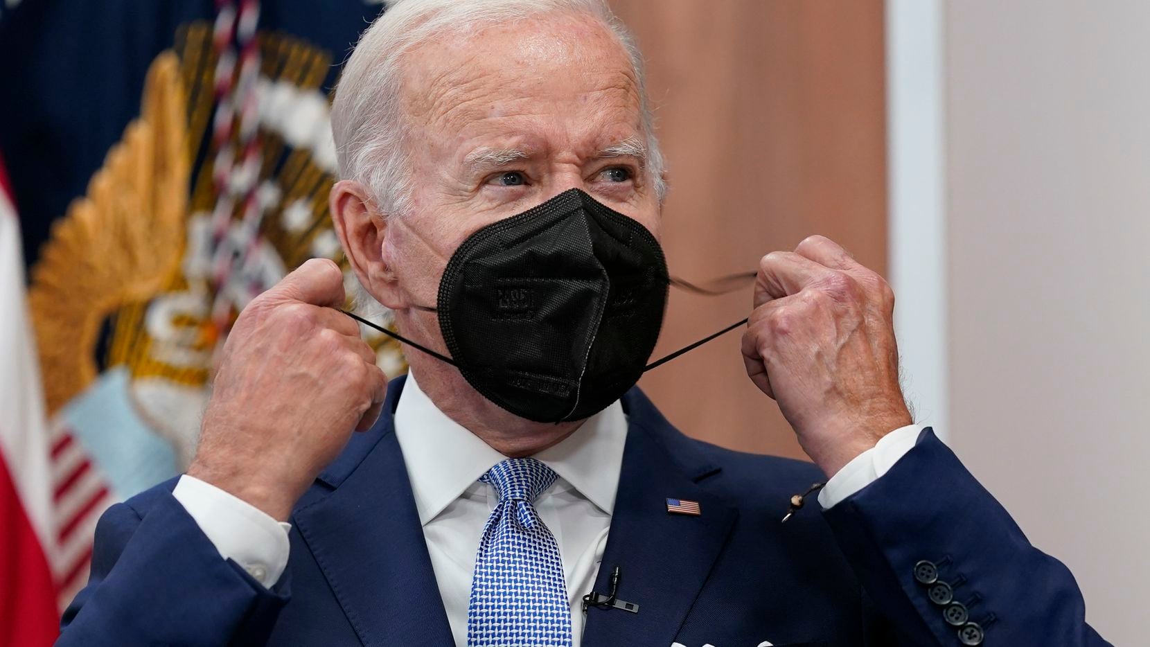 FILE - President Joe Biden removes his face mask as he arrives to speak about the economy...