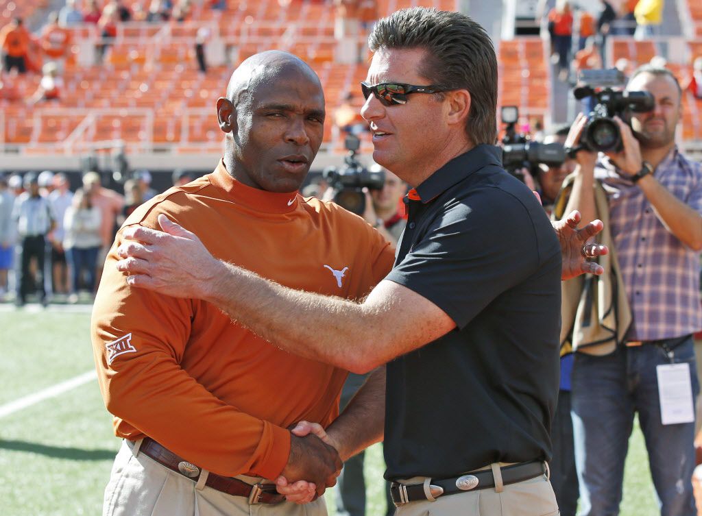 Texas head coach Charlie Strong, left, shakes hands with Oklahoma State head coach Mike...