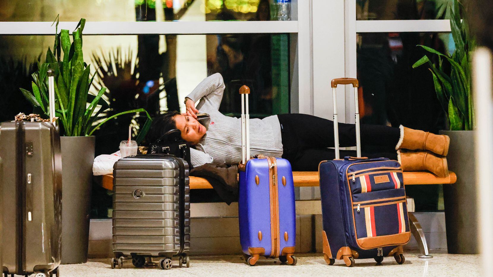 Vicky Bo lies on a bench after her flight to San Jose, Calif., was canceled atDallas Love...