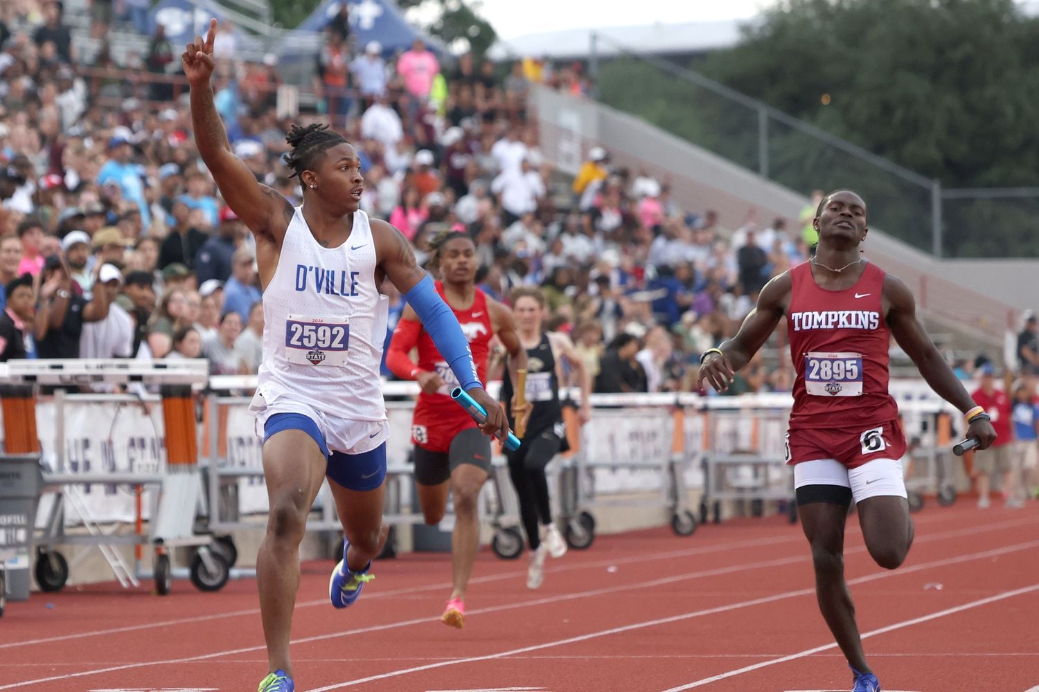 Duncanville anchor leg Dakorien Moore, left, gestures after crossing the finish line first...