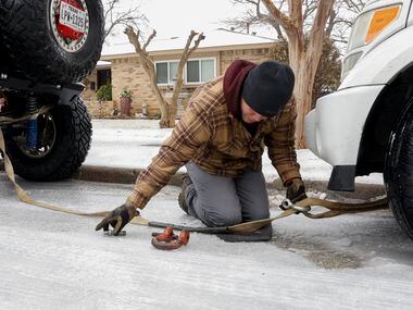 Angel Muniz, Carnales Off Road club member, connects a tow strap to a car stuck on an icy...