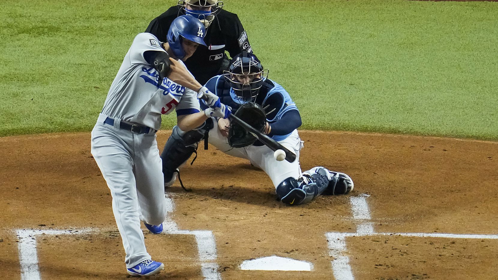 Los Angeles Dodgers shortstop Corey Seager drives in a run with a single as Tampa Bay Rays catcher Mike Zunino works behind the plate during the first inning Game 5 of the World Series at Globe Life Field on Sunday, Oct. 25, 2020. 