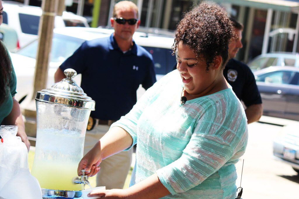 Mia Cagle fills a cup of lemonade for a Denton officer Thursday on the lawn of the Denton...