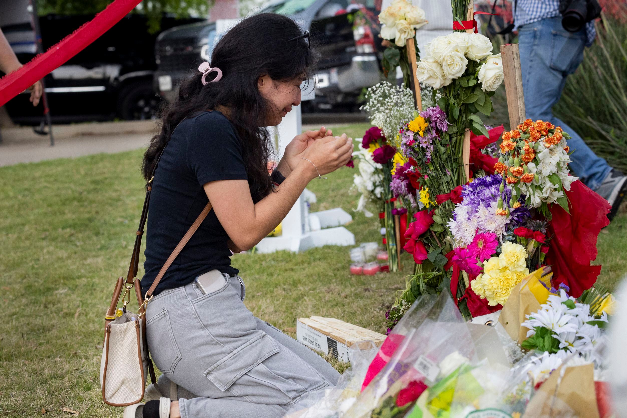 Citaly Ramirez, who witnessed the shooting, cries as she kneels at the memorial outside the...