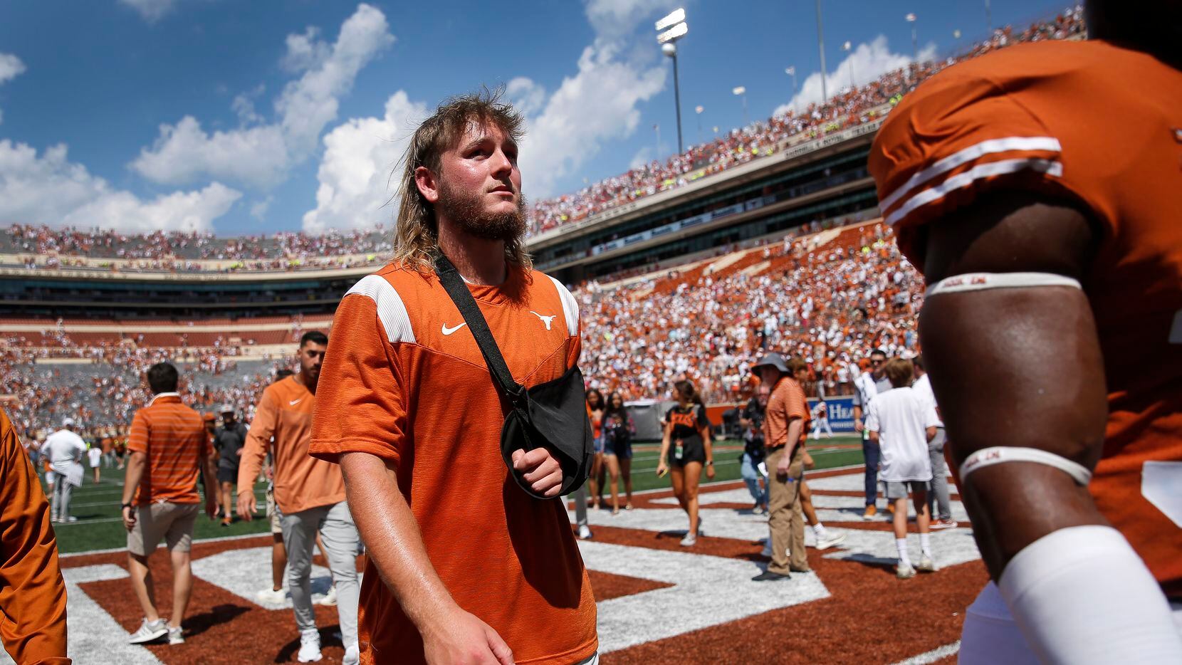 With his arm in a sling, Texas Longhorns quarterback Quinn Ewers walks off the field...