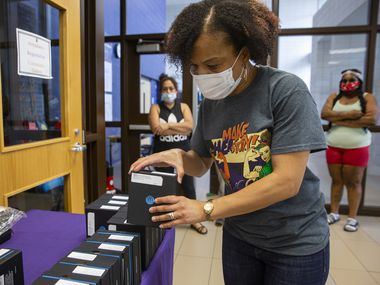 Parents wait as Principal Gabrelle Dickson grabs a WiFi hotspot provided by DISD for students at Young Women's STEAM Academy at Balch Springs on April 24, 2020 in Dallas. A district survey found that 30% of families responded that they didn't have internet at home.