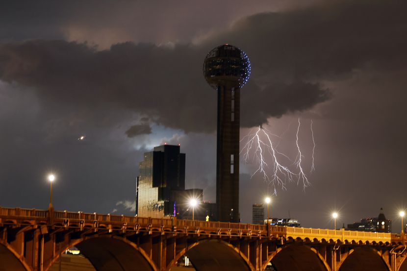 Lighting from a passing storm strikes in the distance behind Reunion Tower in downtown Dallas.