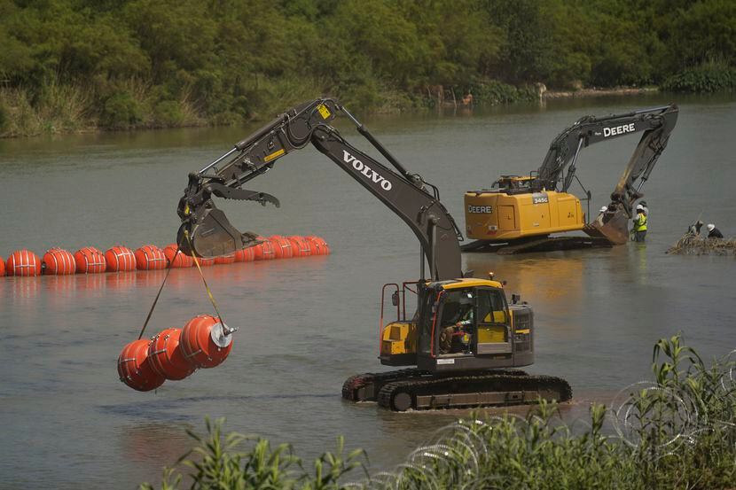 Workers continue to deploy large buoys to be used as a border barrier along the banks of the...