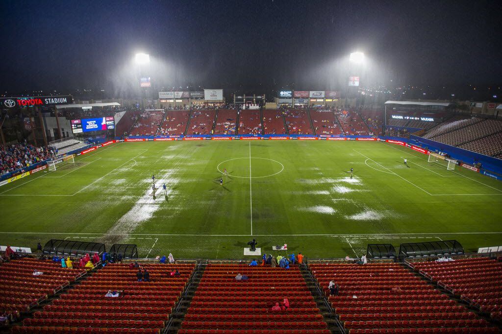 Workers try to squeegee the field during a weather delay in the first half a soccer game...