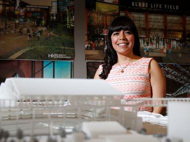 Aguirre poses for a portrait in front of a model of Globe Life Field near her desk at HKS.