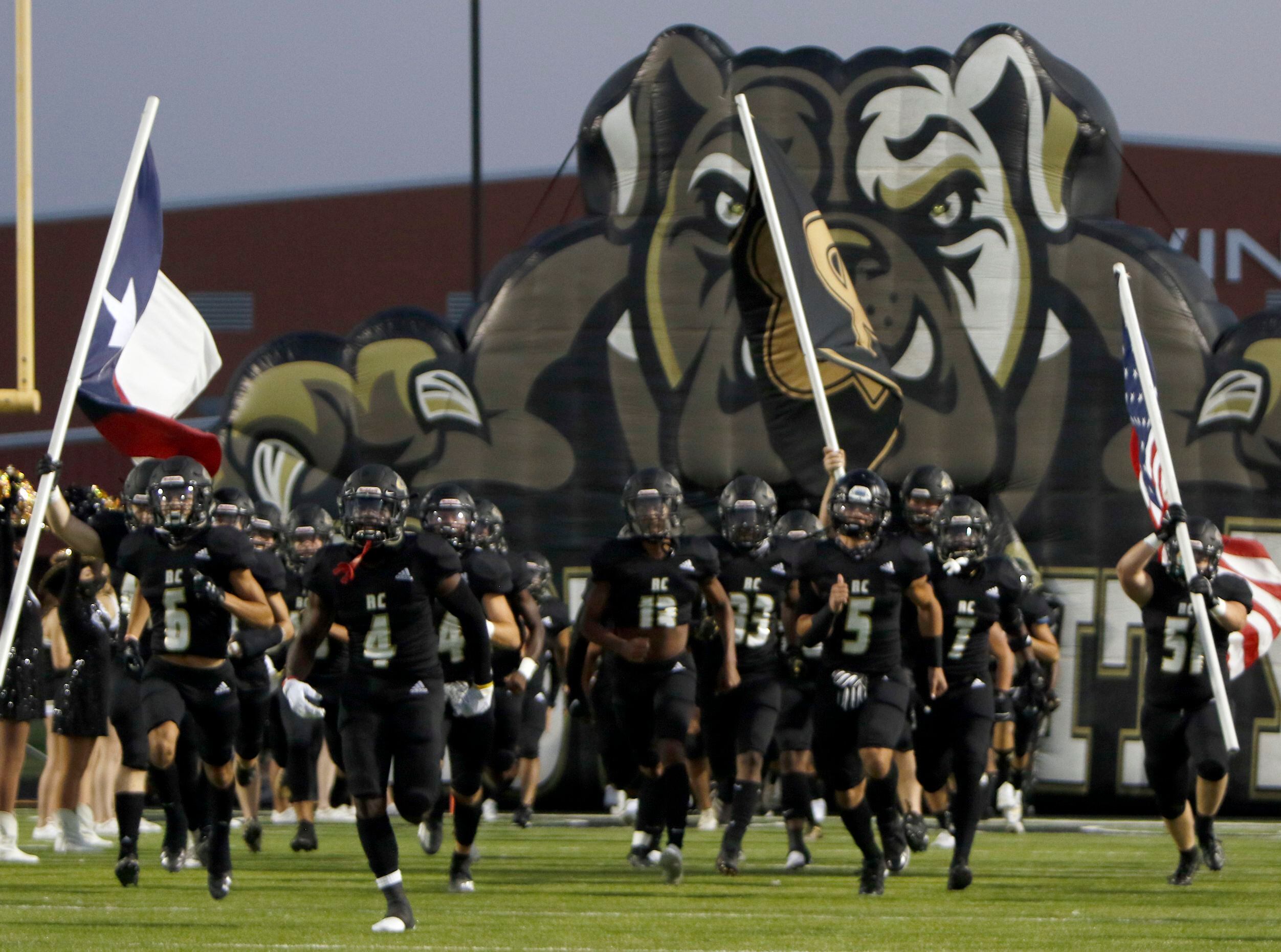 Members of the Royse City Bulldogs storm the field as they emerge from their team inflatable...