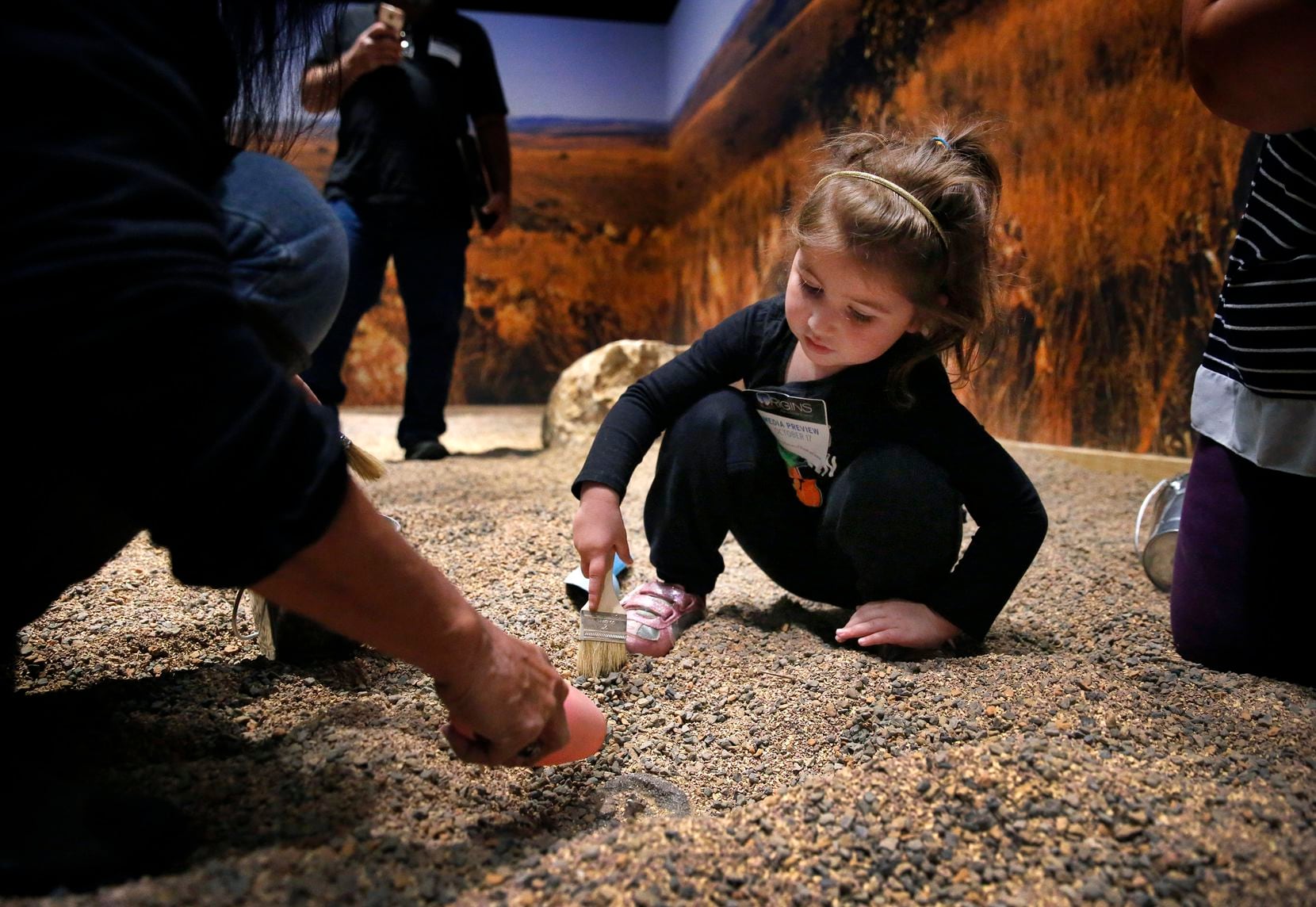 Lily Torrence digs for a fossil in the dig site interactive area of the Perot Museum of Nature and Science's special exhibit "Origins: Fossils From the Cradle of Humankind," which is on display through March 22.