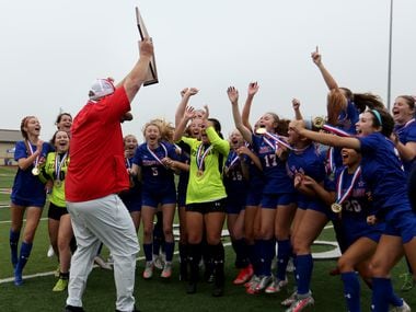Midlothian Heritage head coach Gerald Slovacek cheers with his players as he holds up the trophy during their win over Calallen at their UIL 4A girls State championship soccer game at Birkelbach Field on April 16, 2021 in Georgetown, Texas.