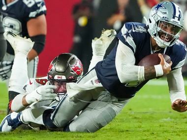 Dallas Cowboys quarterback Dak Prescott (4) is tripped up by Tampa Bay Buccaneers linebacker Joe Tryon-Shoyinka (9) during the first half of an NFL football game at Raymond James Stadium on Thursday, Sept. 9, 2021, in Tampa, Fla.