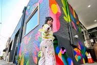 Mariell Guzman poses in front of her mural collaboration with Dallas-based company LDF Silk.