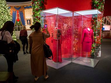 Visitors take photos of a red Oscar de la Renta evening gown worn by Laura Bush is displayed...
