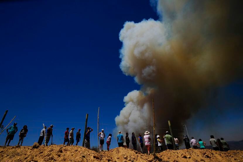 ARCHIVO - Residentes miran una columna de humo que asciende hacia el cielo, en Viña del Mar,...