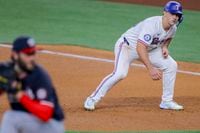 Texas Rangers' Wyatt Langford, right, takes a lead off of first base as Washington Nationals...