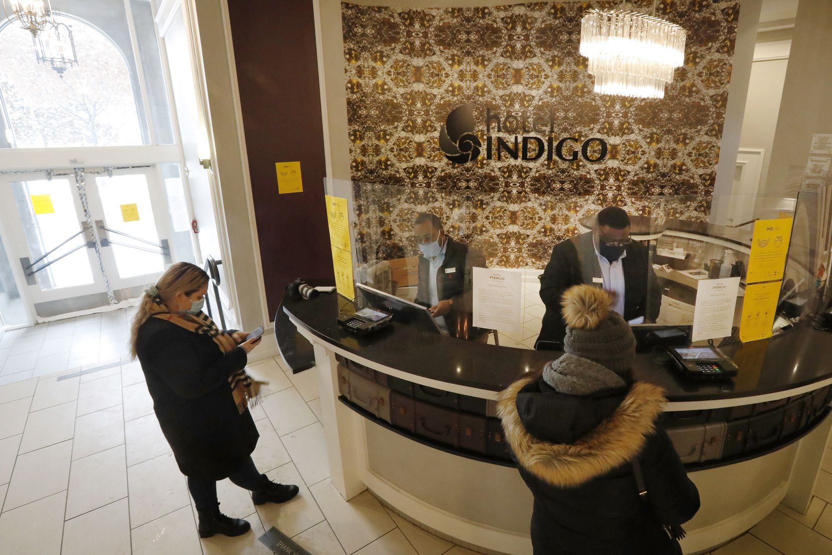 Veronica Quiroz (left) of Seagoville checked her phone as she was being checked in by general manager Marcus Hennigan (center) as Brian Smith checks in another guest at the Hotel Indigo on Main Street in downtown Dallas on Feb. 17. 