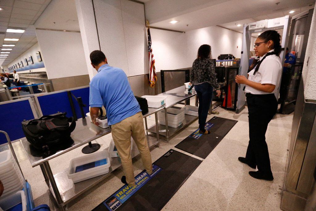 A TSA officer looks on as travelers put their items through an x-ray machine, Tuesday, May...