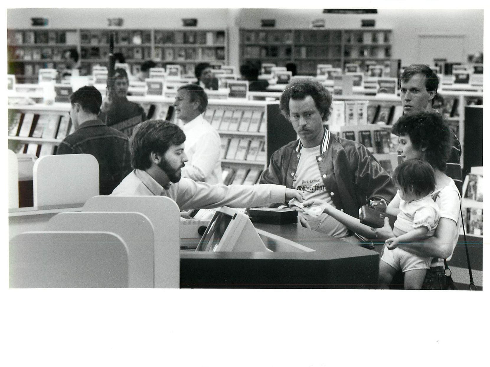Kirk Denny (left) checks on Cindy Burr and her 13-month-old daughter Tracy at Blockbuster...