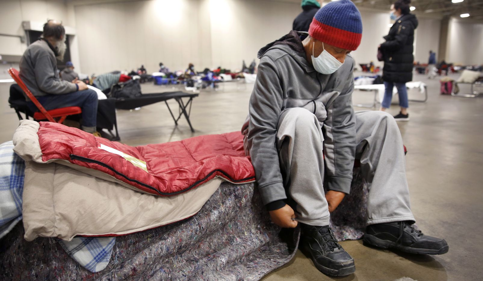 Pierre Scott, a 59 year-old guest and volunteer at a warming center run by OurCalling, changed socks on his socially-distanced cot at the Kay Bailey Hutchison Convention Center in Dallas, Tuesday, February 16, 2021. Scott like a lot of other folks, found refuge from the overnight sub-zero temperatures. (Tom Fox/The Dallas Morning News)