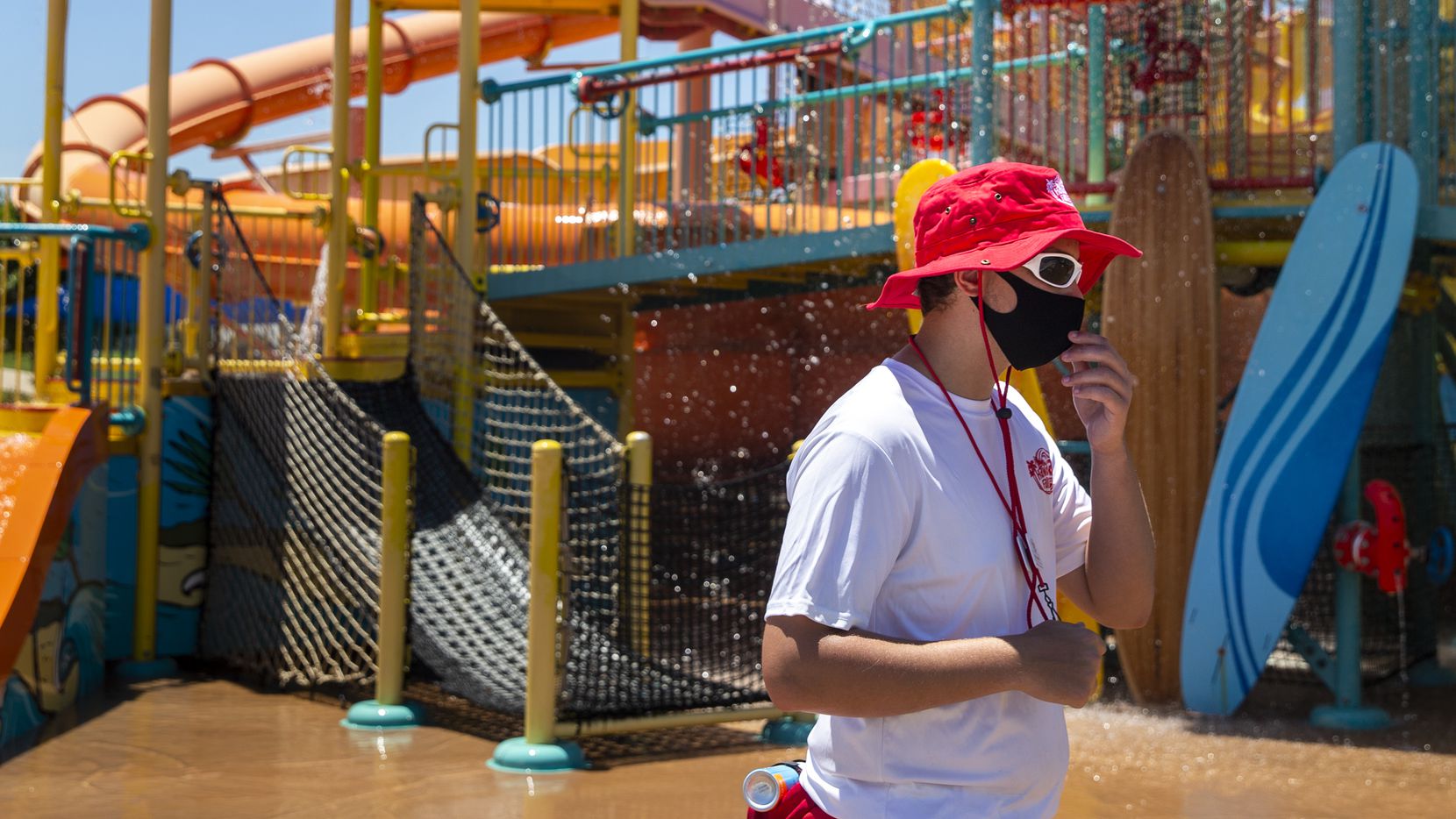 Lifeguard Michael Schmidt adjusts his face mask while monitoring water attractions at the Hawaiian Falls waterpark in Roanoke. Hawaiian Falls was one of the few water parks in North Texas to reopen Friday.