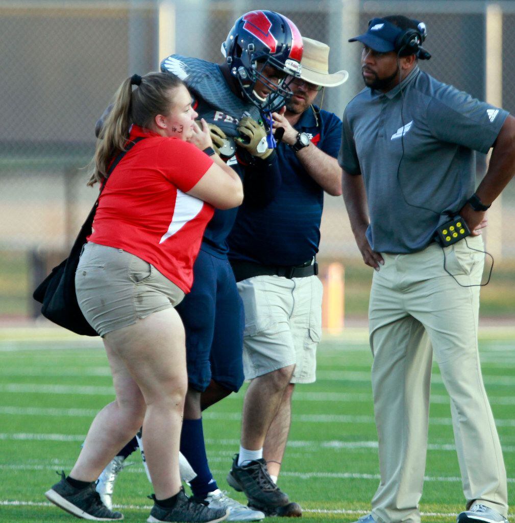 Trainers and coaches help Bishop Dunne LB Brennon Scott (6) from the field, after he was...
