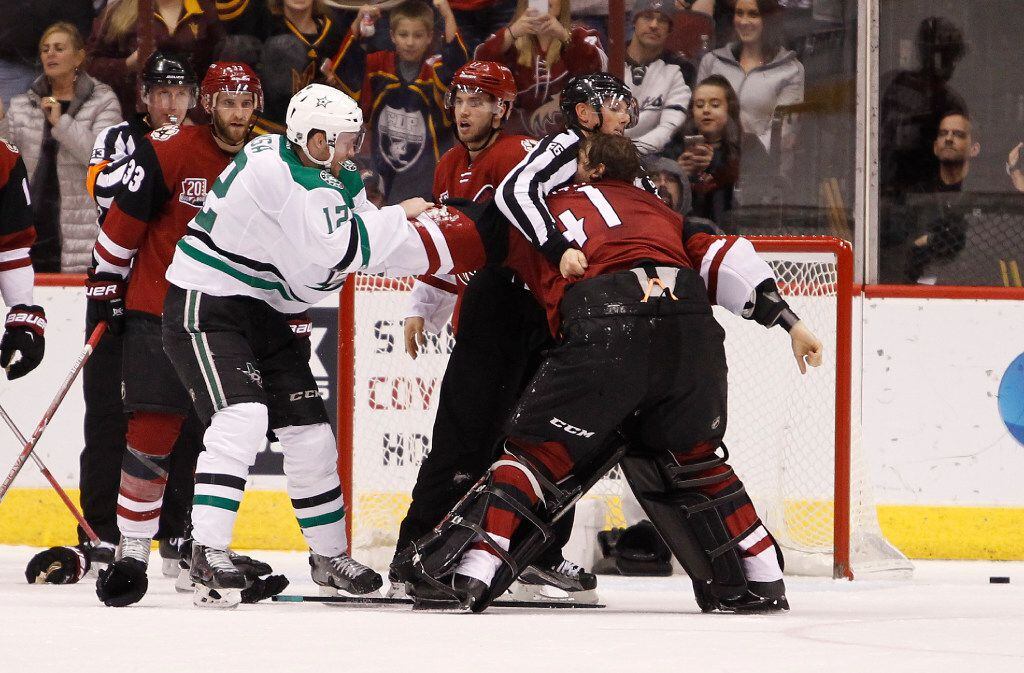 Arizona Coyotes goalie Mike Smith (41) is restrained by linesman Darren Gibbs as he tries to...