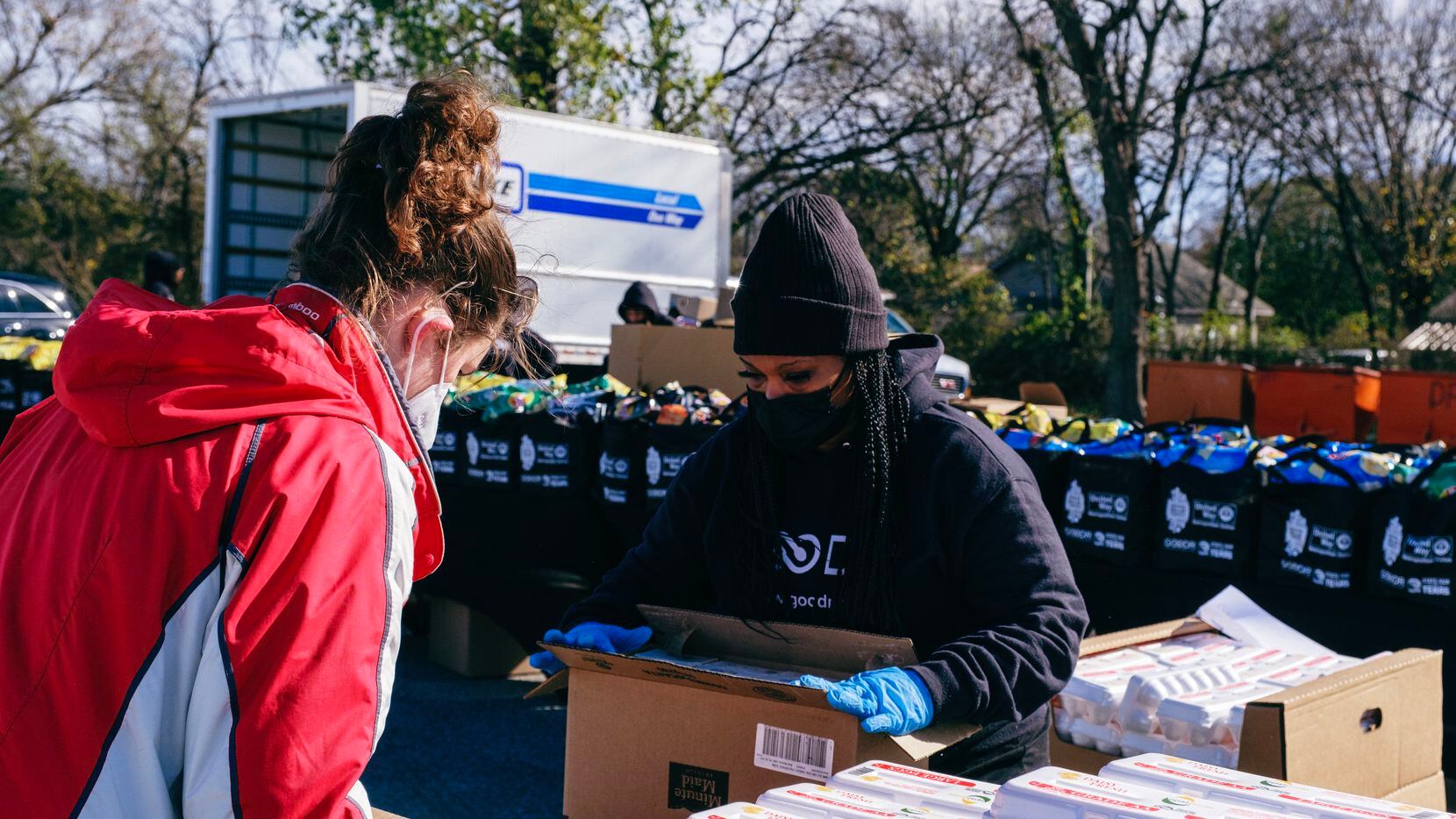 Employees with Goodr prepare for a pop-up grocery event wearing masks and opening boxes.