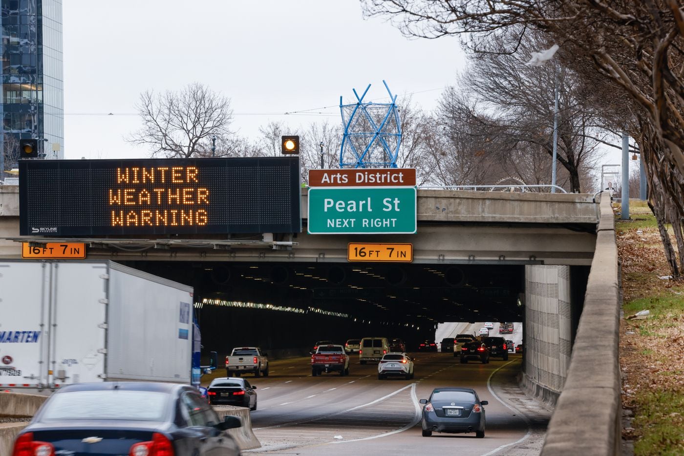 Winter weather warnings flash above traffic on Woodall Rodgers Freeway in downtown Dallas on...