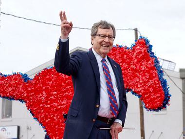SMU president R. Gerald Turner waves to the crowd aboard an SMU float during the Martin...