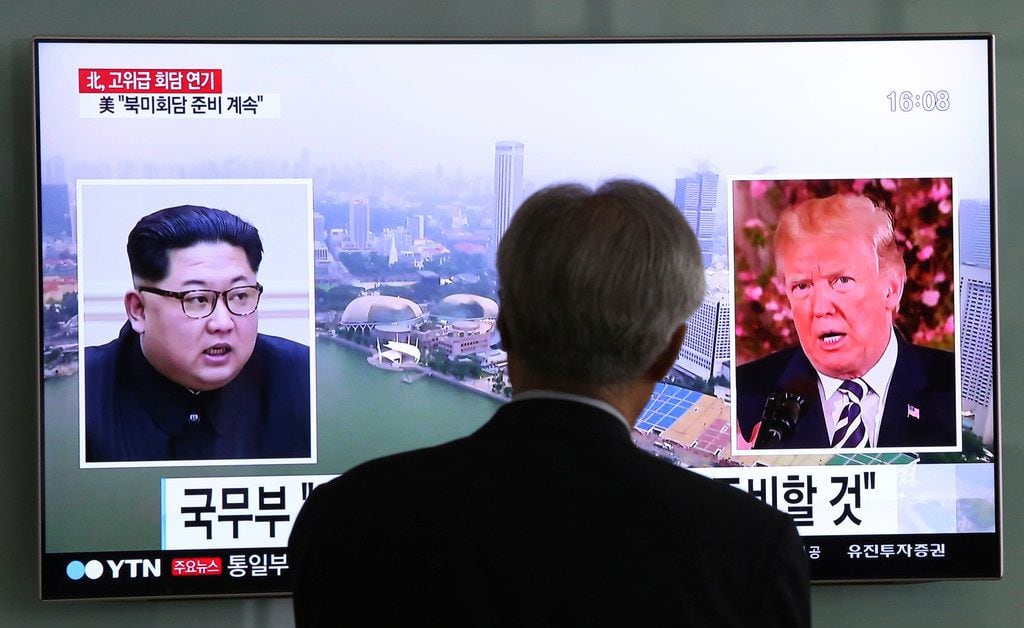 A man watches a TV screen showing file footage of U.S. President Donald Trump, right, and...