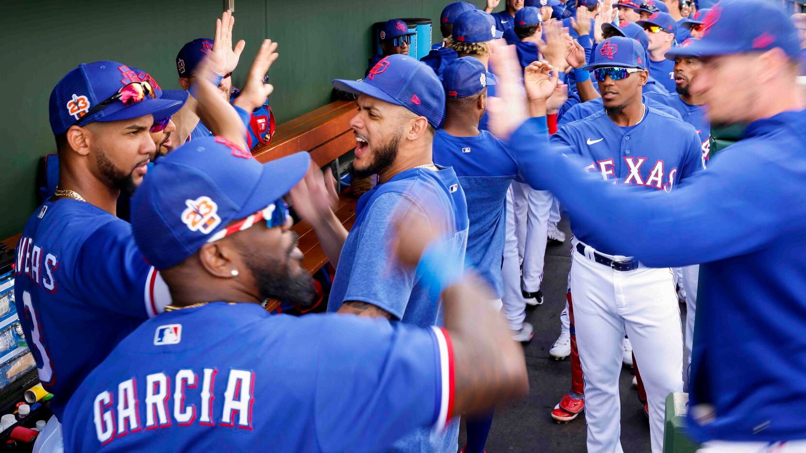 Texas Rangers players, including pitcher Jonathan Hernández (center), exchange high-fives...