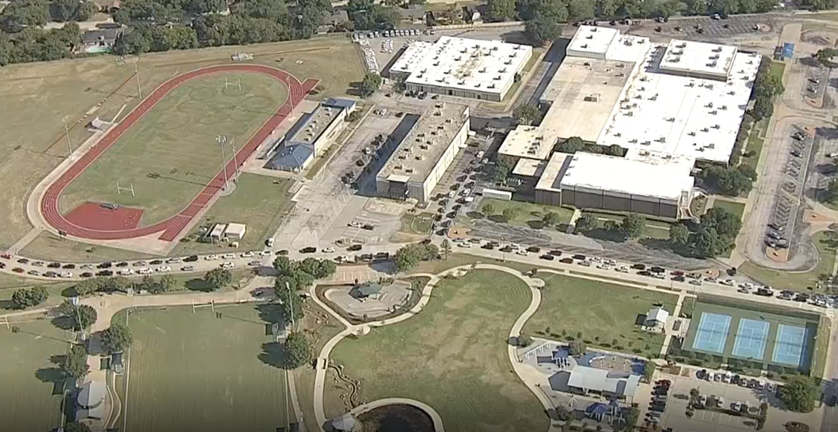 Un toma aérea de KXAS-TV (NBC 5) muestra la fila de autos para retirar aparatos electrónicos en la escuela Brooks Wester en el distrito de Mansfield. Algunos padres de familia reportaron una espera de hasta 10 horas.