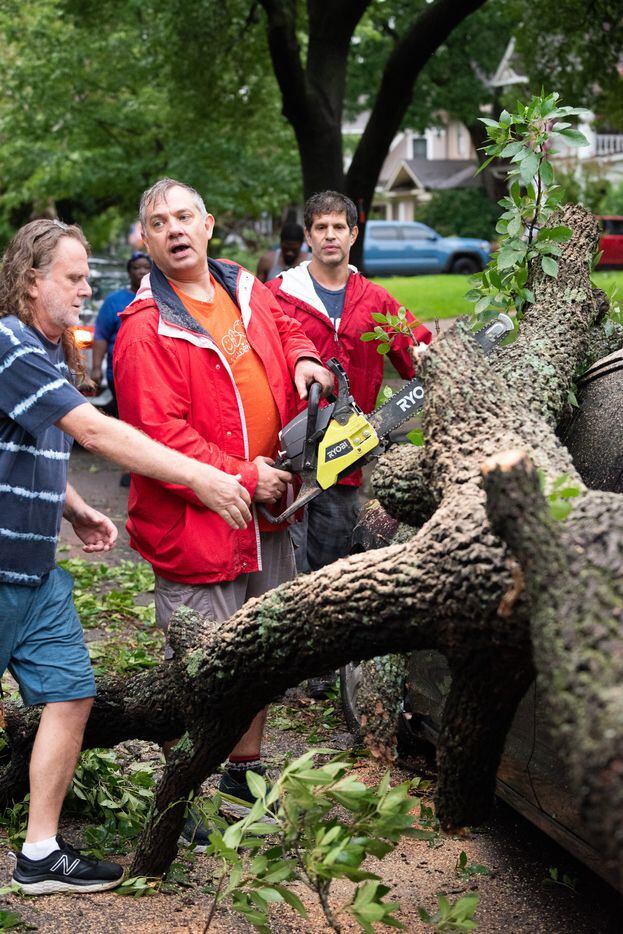Mark Guest, 55, uses a chainsaw to cut portions of a tree that came crashing down on a...