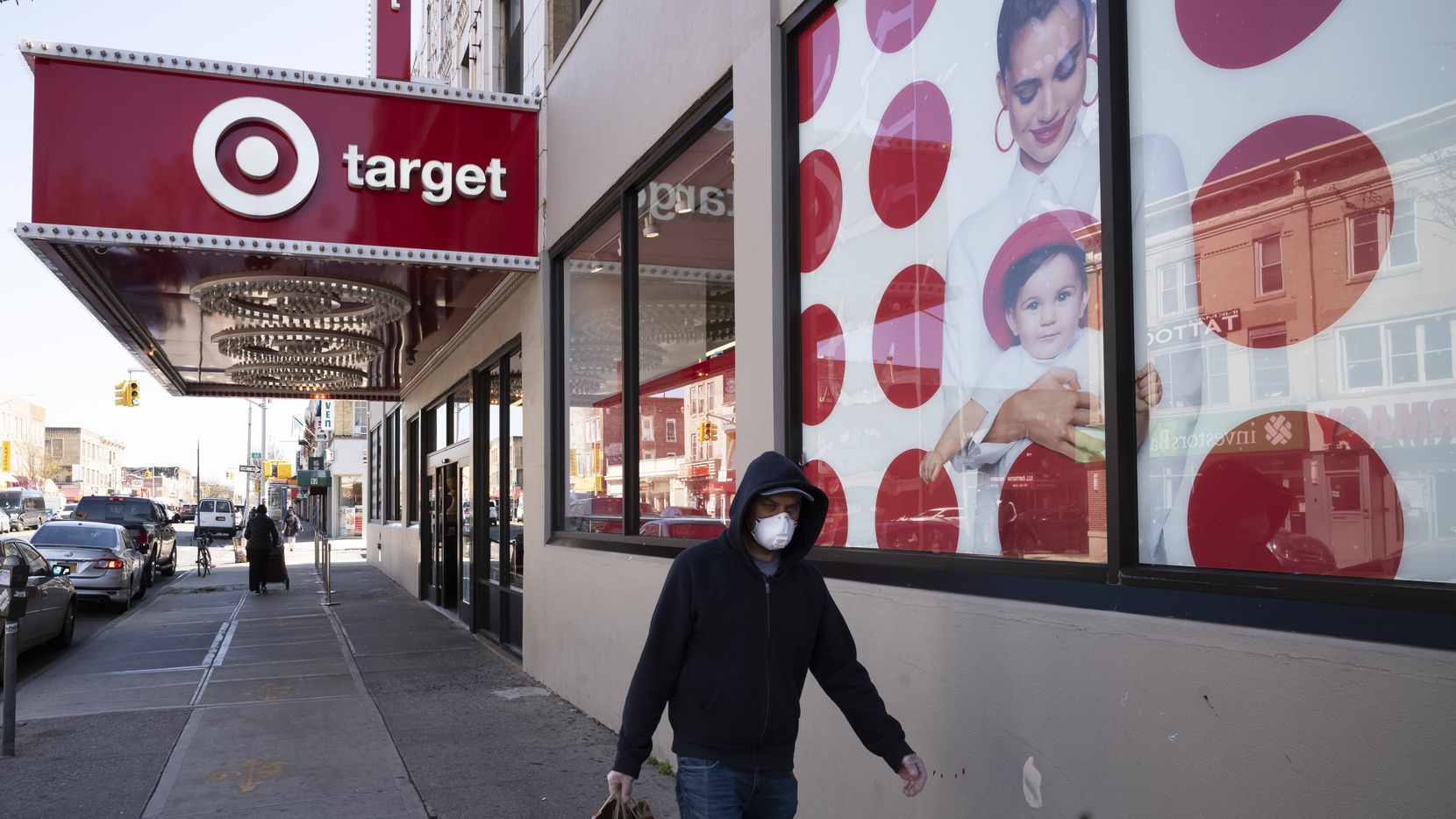 A customer wearing a mask carries his purchases as he leaves a Target store during the...