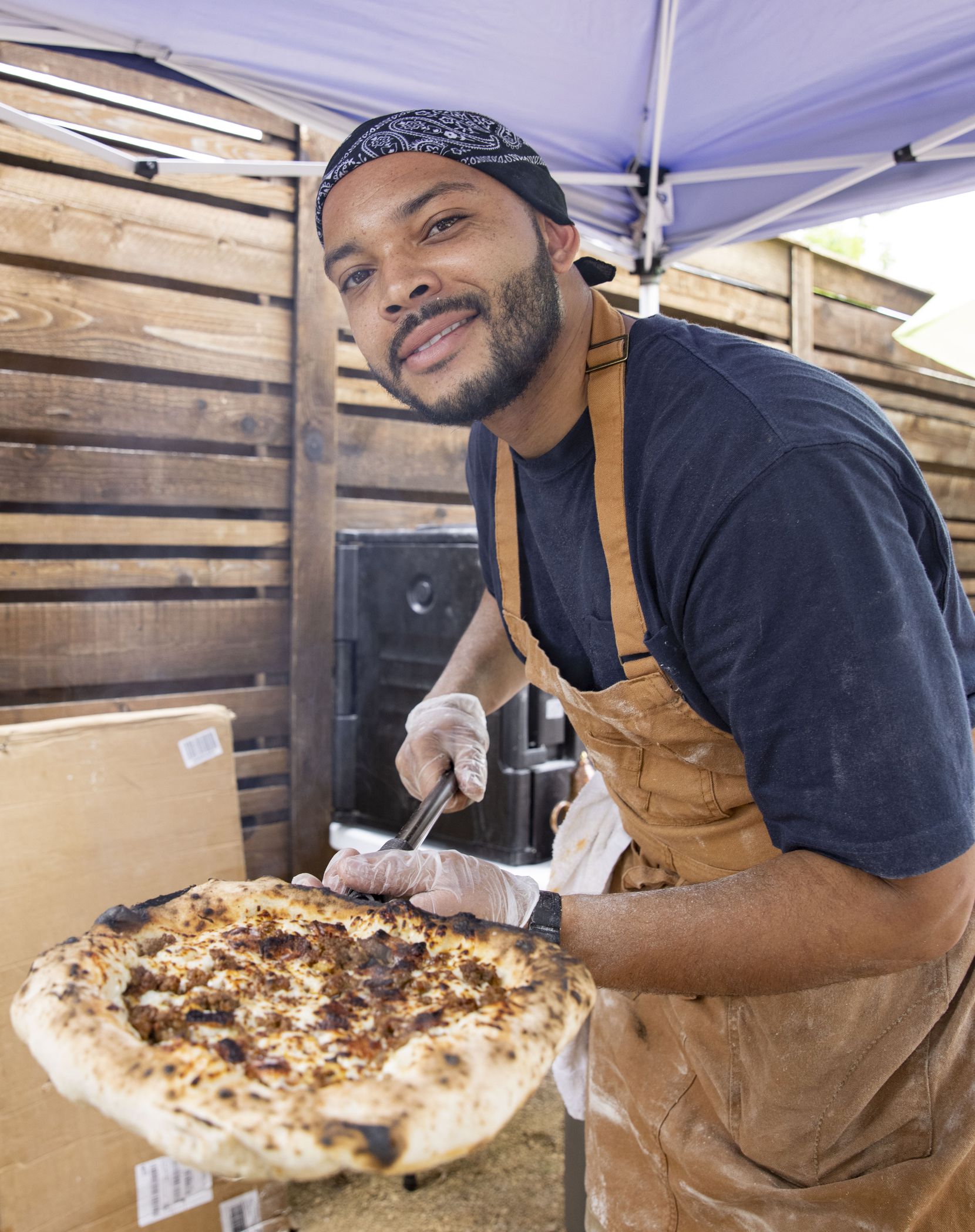 Desmon Coleman, owner of Hustle Town Pizza, offers a hamburger pizza at Hop and Sting Brewing Co. in Grapevine. 