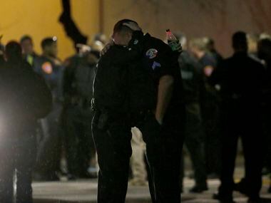 Police officers console each other Tuesday night outside the emergency room at Medical City...