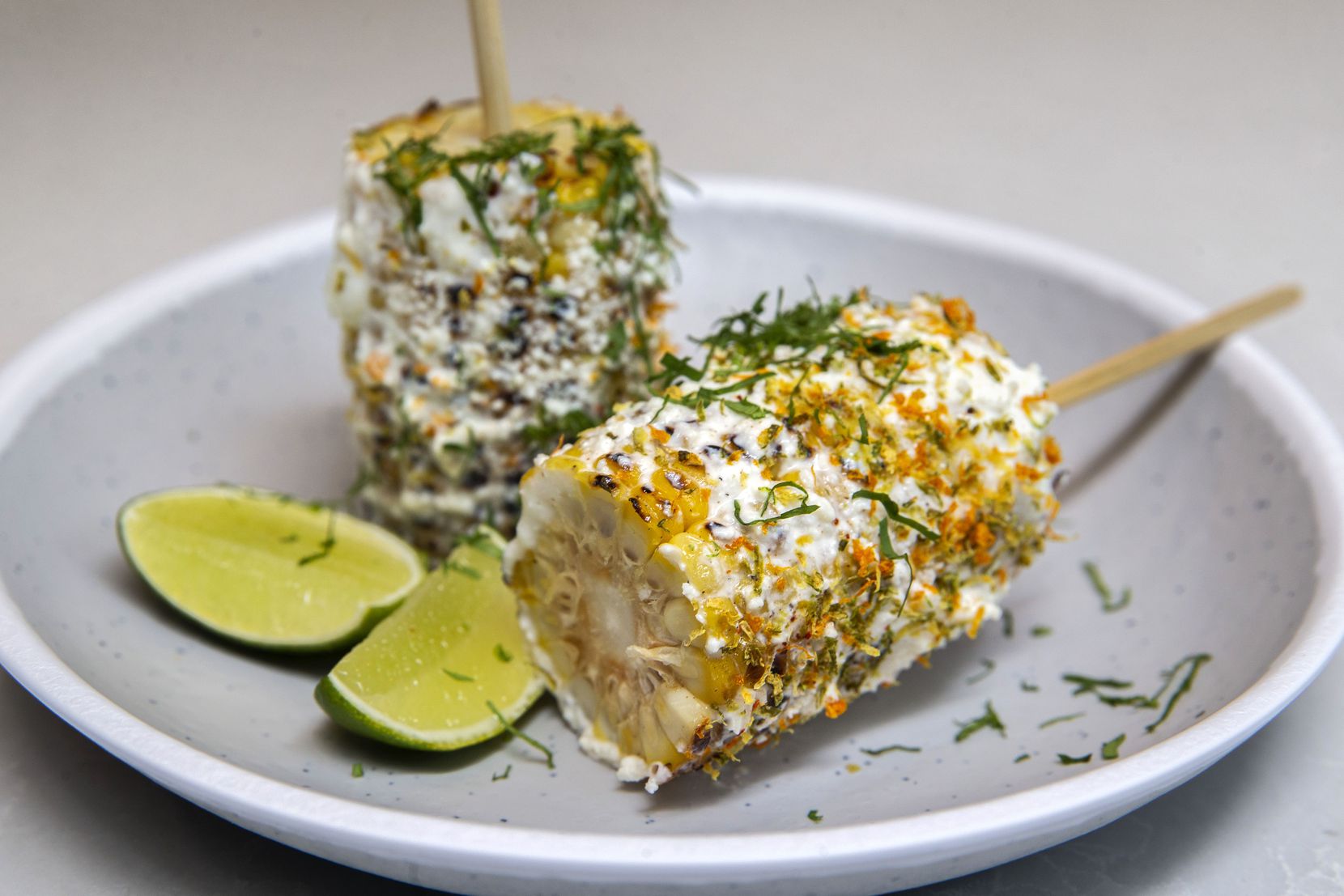 Elote on a Stick is topped with ricotta, cotija, chili-citrus sprinkle and cilantro, with...