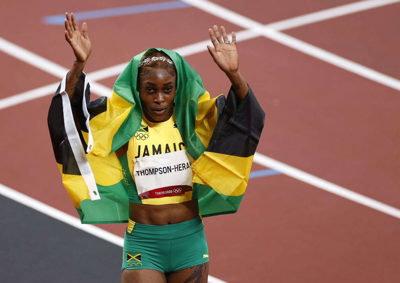 Jamaica’s Elaine Thompson-Herah holds up the Jamaican flag after winning the women’s 100...