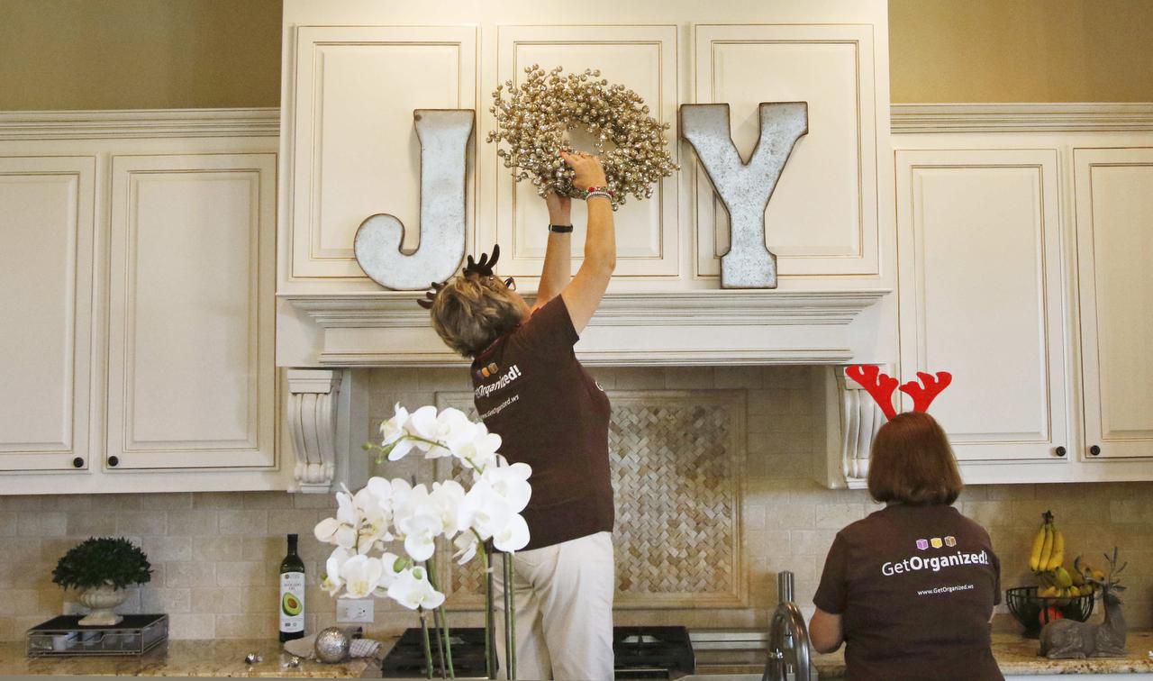 
Karla Koehler climbs high to place a wreath in just the right place in the kitchen of Kathryn Brensinger, of Southlake.
