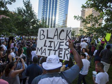 Ferelle Woodhouse holds a "Black Lives Matter" sign joins other protestors at a rally in...