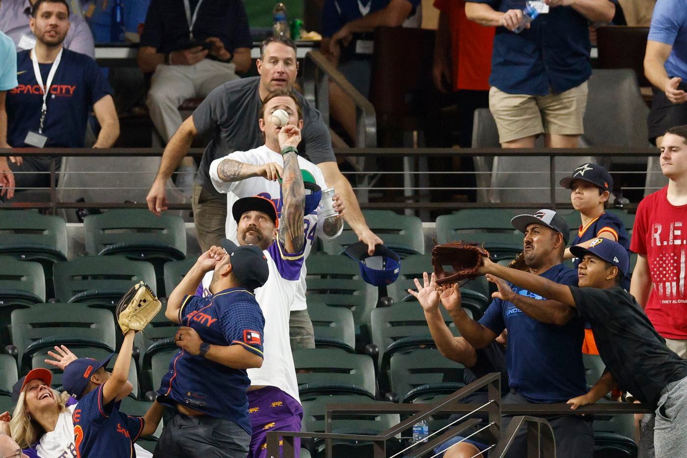 Fans reach for a foul ball during the fourth inning of a gam between the Texas Rangers and...
