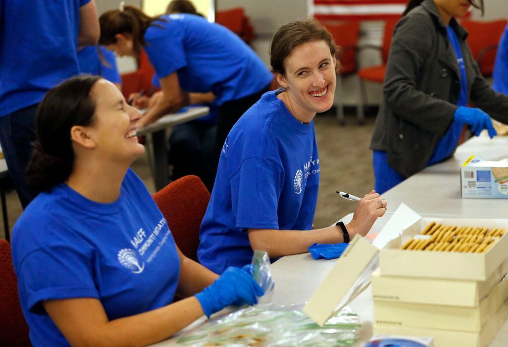 Shannon Carroll (left) of McKinney shared a laugh with Kendall Howard of Plano during a cookie packing event for the homeless at Halff Associates in Richardson in 2018. The cookies were delivered to SoupMobile in Dallas to be given out to the homeless.